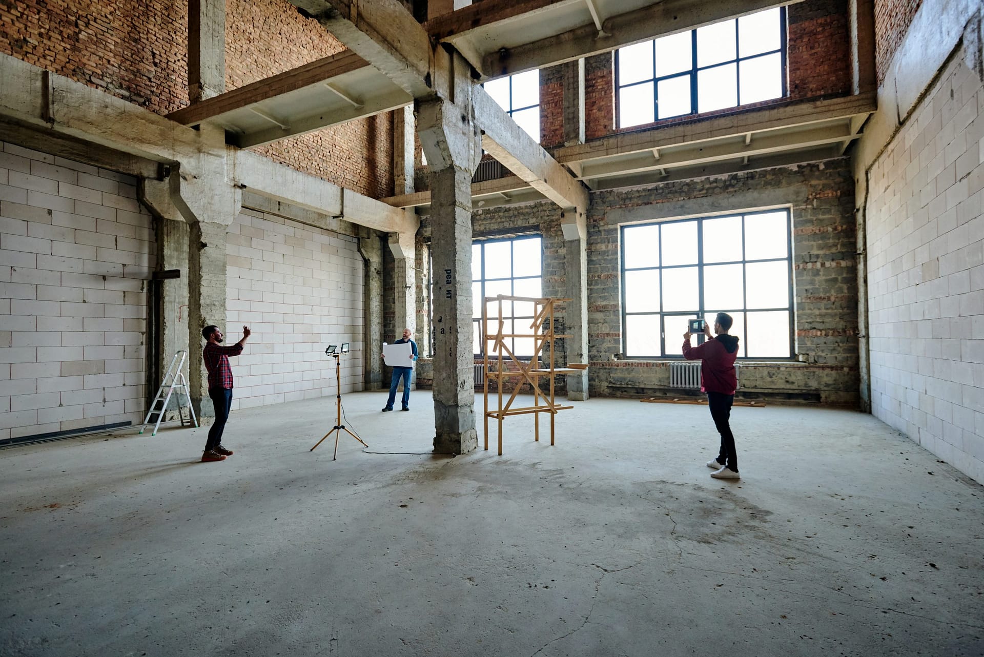 Two young contractors photographing unfinished structure inside building